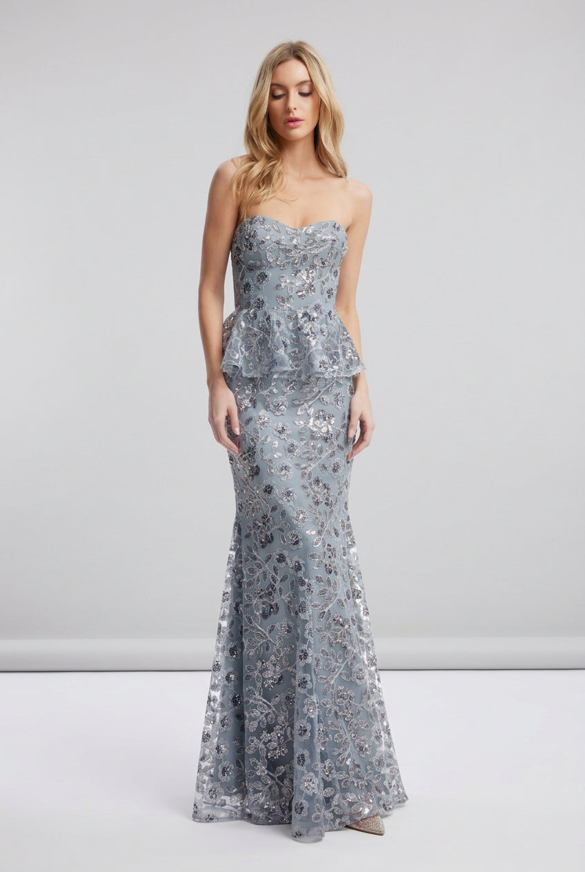 Woman wearing a strapless floral evening gown on a white background